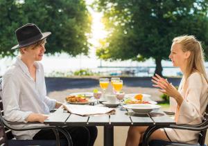 two people sitting at a table with food and drinks at Hotel Bellevue in Hjo
