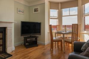 a living room with a television and a table with chairs at Pilgrim's Lookout Whitstable Holiday Home in Whitstable