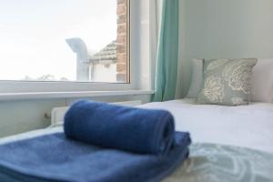 a blue blanket sitting on a bed next to a window at Pilgrim's Lookout Whitstable Holiday Home in Whitstable
