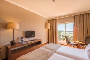 a hotel room with a bed and a television at Vila Gale Albacora in Tavira
