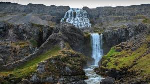 a waterfall on the side of a mountain at Harbour Inn - Guesthouse in Bíldudalur