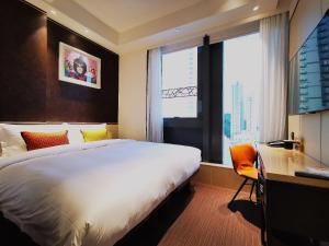a hotel room with a bed and a desk and a window at E Hotel Hong Kong in Hong Kong