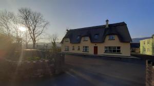 a house with a black roof on top of a wall at Inspiration Lodge in Anascaul