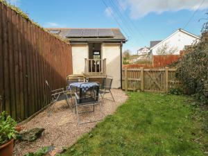 a backyard with a table and chairs and a fence at Springfield Cottage in Bideford