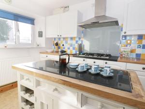 uma cozinha com armários brancos e um balcão preto em Fern Cottage em Saltburn-by-the-Sea