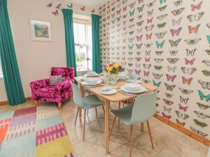 ein Esszimmer mit einem Tisch und Stühlen sowie einer Schmetterlingstapete in der Unterkunft Adams House in Eyemouth
