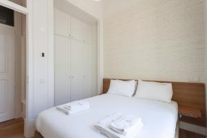 um quarto com uma cama branca com duas toalhas em FLH Restauradores Bright Flat em Lisboa