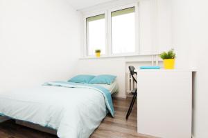 a white bedroom with a bed and a desk at Blue River - Niedzwiedzia in Wrocław