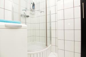 a white tiled bathroom with a shower and a sink at Blue River - Niedzwiedzia in Wrocław