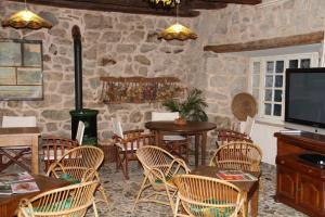 a dining room with tables and chairs and a tv at Hôtel Auberge du Combaïre in Laguiole