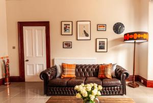 sala de estar con sofá de cuero marrón en Nelson Manor en Dundee