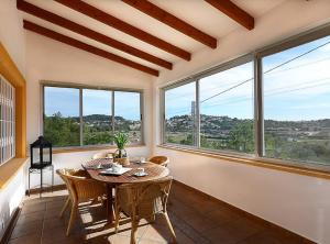 a dining room with a table and chairs and windows at Villa Iris - Plusholidays in Calpe