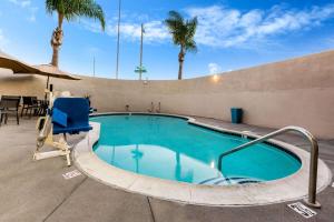 a swimming pool with a blue chair and palm trees at La Quinta by Wyndham San Diego Mission Bay in San Diego