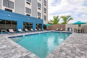 a pool at a hotel with chairs and umbrellas at Comfort Suites Stuart-Hutchinson Island in Stuart