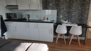 a kitchen with white cabinets and two white chairs at B&B Bij Bronckhorst in Steenderen