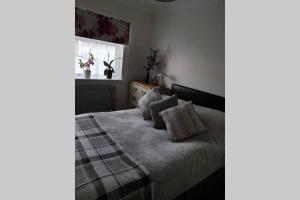 een slaapkamer met een bed met kussens en een raam bij A home away from home with a big welcome in Slades Green