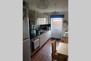 a kitchen with a table and a dining room at A home away from home with a big welcome in Slades Green