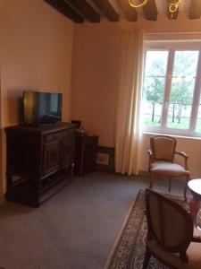 sala de estar con TV, mesa y ventana en Auberge de villechaume, en Sennely
