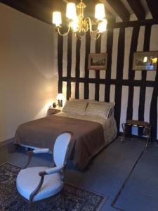 a bedroom with a bed and a chair and a chandelier at Auberge de villechaume in Sennely