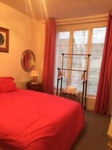 a bedroom with a red bed and a window at Auberge de villechaume in Sennely