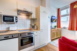 a kitchen with white appliances and a red couch at Haus Meerblick - 12 in Ahlbeck