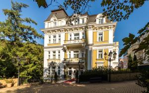 un edificio blanco y amarillo con un letrero. en Hotel Vila Livia, en Karlovy Vary