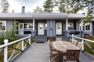 a house with a wooden deck with a table and chairs at Punkaharju Resort in Punkaharju