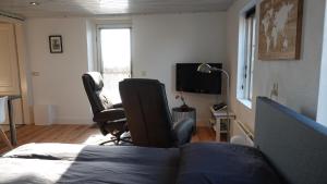 a bedroom with a bed and two chairs and a television at B&B Bij Bronckhorst in Steenderen