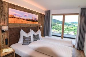 a bedroom with two beds and a large window at Aurela Mountain Chalets in Selva di Val Gardena