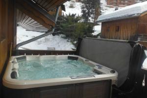 bañera de hidromasaje en una terraza con nieve en el suelo en Chalet l'écureuil, en Méribel