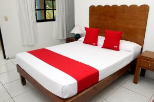 - une chambre avec un grand lit et des oreillers rouges dans l'établissement OYO Hotel Miramar, Loreto, à Loreto