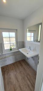 baño blanco con lavabo y ventana en Ferienhaus Südwesthörn, en Emmelsbüll-Horsbüll