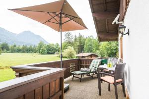 um pátio com uma mesa, cadeiras e um guarda-sol em Ferienhaus Eva em Ruhpolding