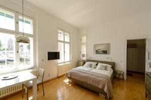 a bedroom with a bed and a desk and windows at Fewo auf der Dominsel - SEEROSE in Brandenburg an der Havel