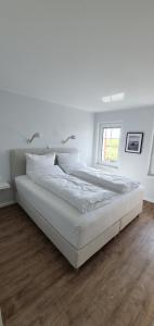 Un dormitorio blanco con dos camas y una ventana. en Ferienhaus Südwesthörn, en Emmelsbüll-Horsbüll