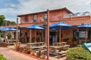um restaurante com mesas de madeira e guarda-sóis azuis em Pet-Friendly, King Bed, Close to Siesta Beach, Restaurants, Shopping em Sarasota