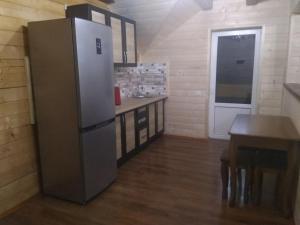 eine Küche mit einem großen Kühlschrank und einem Tisch in der Unterkunft Приватна садиба "Гереджука" in Worochta