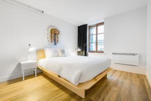 Un dormitorio blanco con una cama grande y una ventana en Les Lofts St-Paul - Par Les Lofts Vieux-Québec, en Quebec