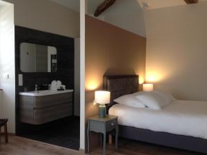 a bedroom with a bed and a sink and a mirror at La Clé du Puy in Cabariot
