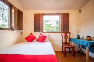 a room with a bed and a desk and a window at OYO Cabañas Abril, Mazunte in Mazunte