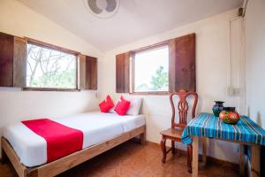 a bedroom with a bed and a chair and two windows at OYO Cabañas Abril, Mazunte in Mazunte