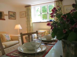 a living room with a table with plates and wine glasses at Mayfly Cottage in Quenington
