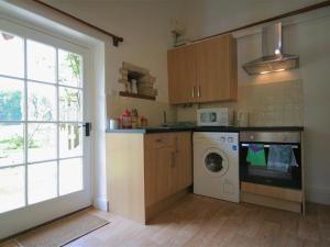 a kitchen with a washing machine and a window at Mayfly Cottage in Quenington