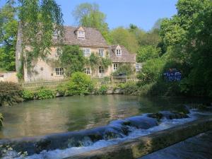 a house and a river in front of a building at Mayfly Cottage in Quenington