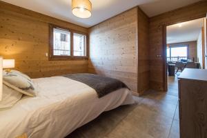 um quarto com uma cama numa parede de madeira em ODYSSEE CRC01 Appartement traversant sur les pistes em La Toussuire