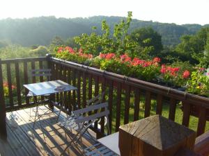 a table and chairs on a balcony with flowers at GITE MASKALI in Thenon