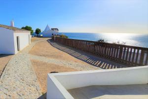 a walkway next to the ocean with a wooden fence at LovelyStay - The Algarvean Oasis in Armação de Pêra