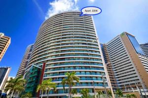 un edificio alto con un cartel que lee los siguientes honorarios en Modern Beachfront Apartment w. Magnificent Seaview en Fortaleza