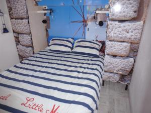 een bed met blauwe en witte gestreepte lakens in een kamer bij La Pergola de la Plage in Gruissan