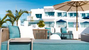 a patio with chairs and an umbrella and a building at CalaLanzarote Suites Hotel - Adults Only in Playa Blanca